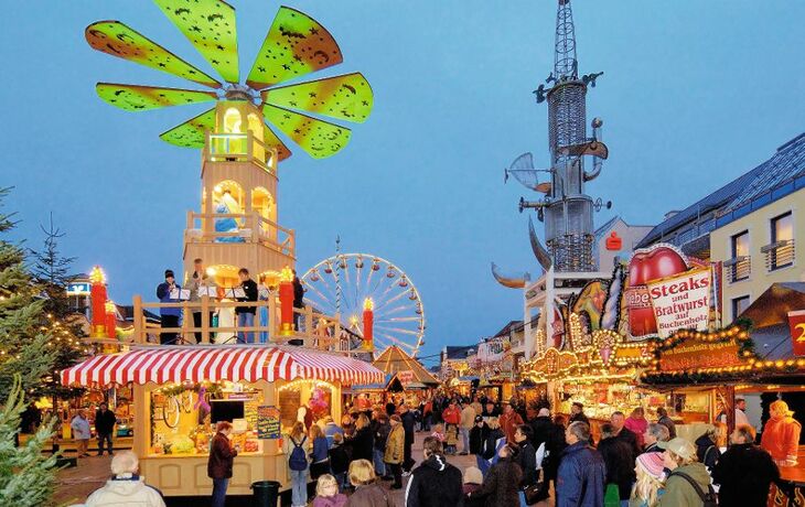 Weihnachtsmarkt in Aurich mit beleuchteten Ständen, Gästen und einem Riesenrad.