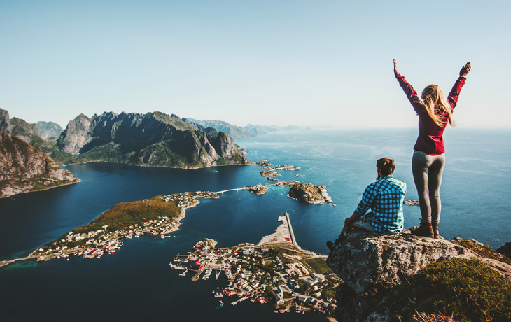 Touristenpaar genießt Panoramablick auf Lofoten-Inseln und Berge in Norwegen.