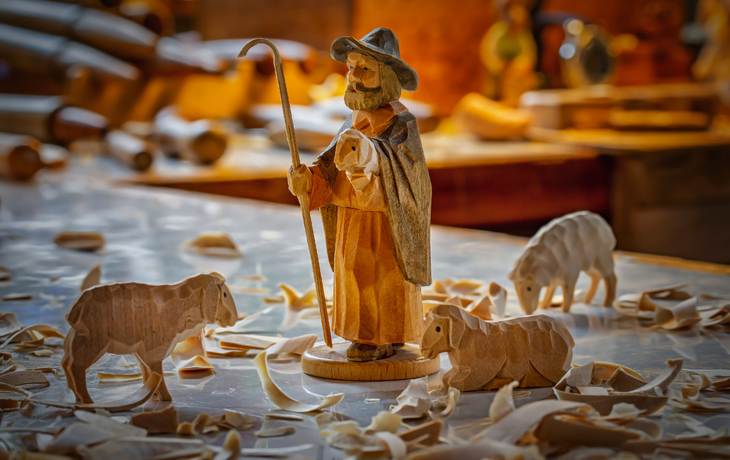 Traditionelle erzgebirgische Holzschnitzerei mit Krippenfiguren in einer Werkstatt.