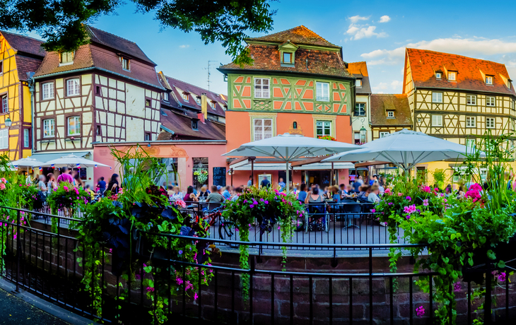 Fachwerkhäuser und Café in Colmar, Frankreich, bei sonnigem Wetter.