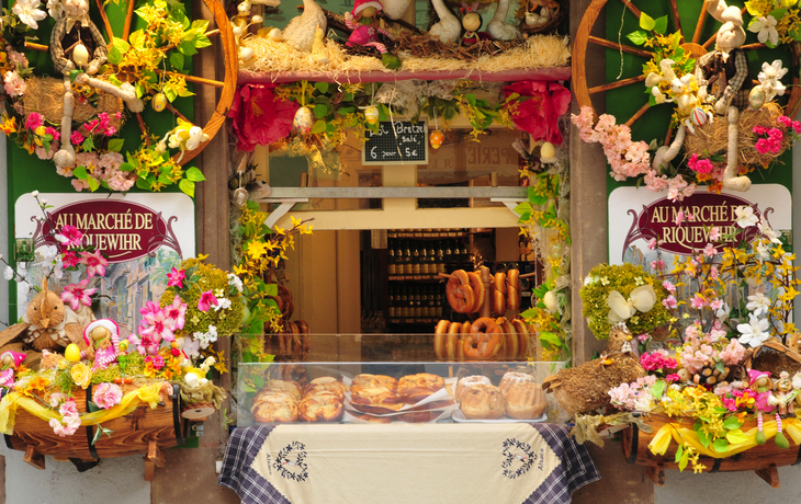 Ein geschmückter Laden in Riquewihr mit Brot und Blumenarrangement.