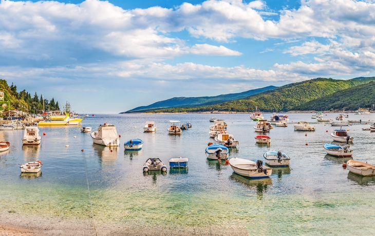Hafen von Rabac in Kroatien mit Booten und Küste im Hintergrund.