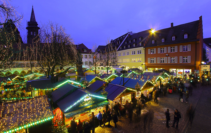 Weihnachtsmarkt in Freiburg im Breisgau mit Lichtern und Menschen im Winter.