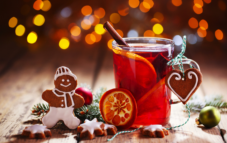 Weihnachtliche Dekoration mit Lebkuchen und heißem Getränk vor unscharfem Hintergrund.