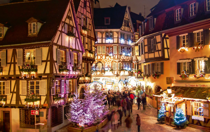 Beleuchtete Fachwerkhäuser und Weihnachtsmarkt in Colmar bei Nacht.