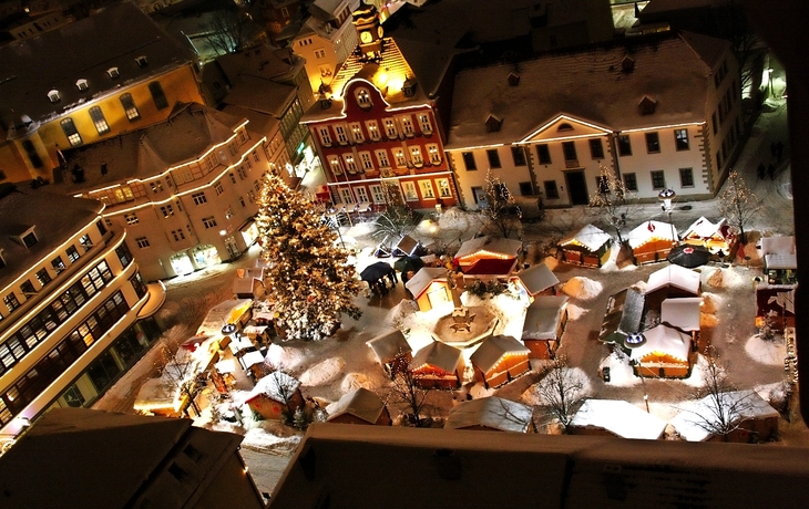 Verschneiter Weihnachtsmarkt in Suhl, Thüringen mit Buden und Lichtern bei Nacht.