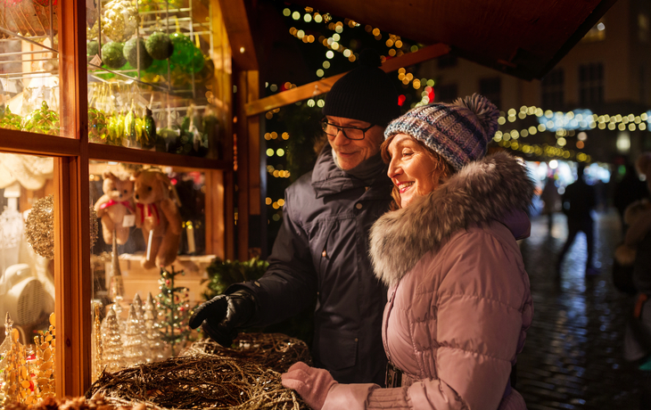 Älteres Paar genießt fröhlich den Weihnachtsmarkt bei Nacht