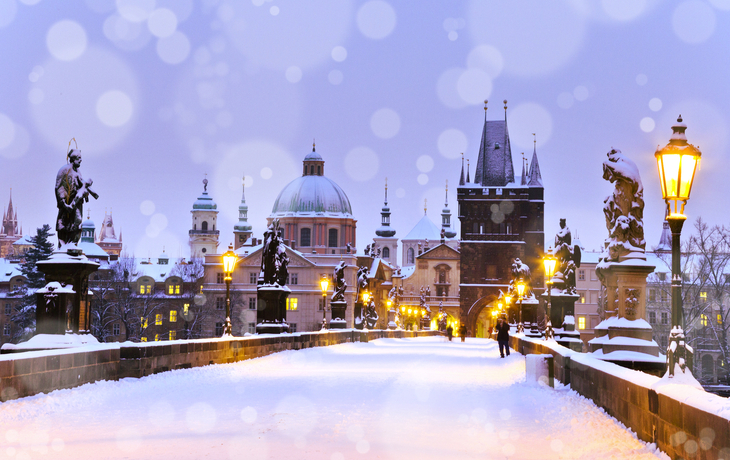 Winterliche Karlsbrücke in Prag, verschneit, mit Architektur und Skulpturen.