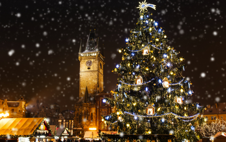 Weihnachtsmarkt auf dem Altstädter Ring in Prag bei Schneefall und Abendbeleuchtung.