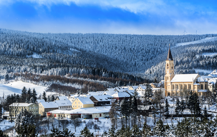 Winterlandschaft in Oberwiesenthal mit Kirche und schneebedeckten Wäldern im Erzgebirge.