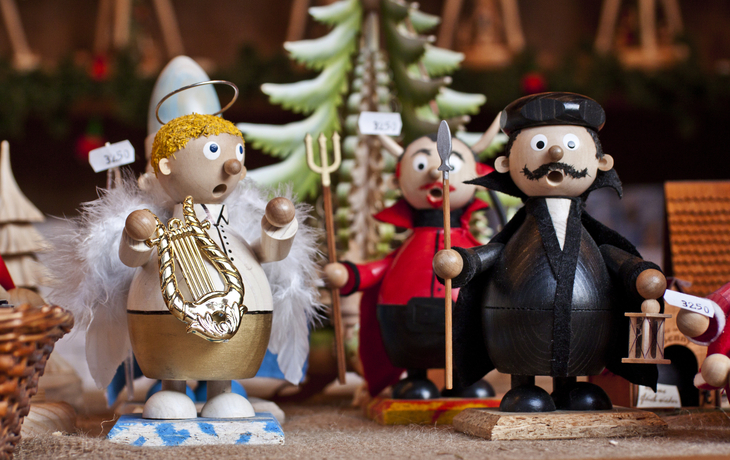 Räuchermännchen aus Seiffen mit Weihnachtsdekoration im Hintergrund.