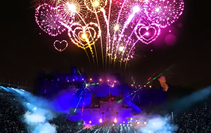 Militärparade vor Edinburgh Castle mit Feuerwerk am Nachthimmel.