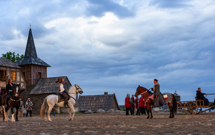 Schauspieler auf Pferden vor historischer Kulisse bei den Störtebeker Festspielen.