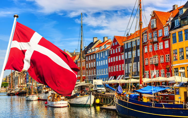 Nyhavn Hafen mit bunten Häusern und dänischer Flagge in Kopenhagen, Dänemark.
