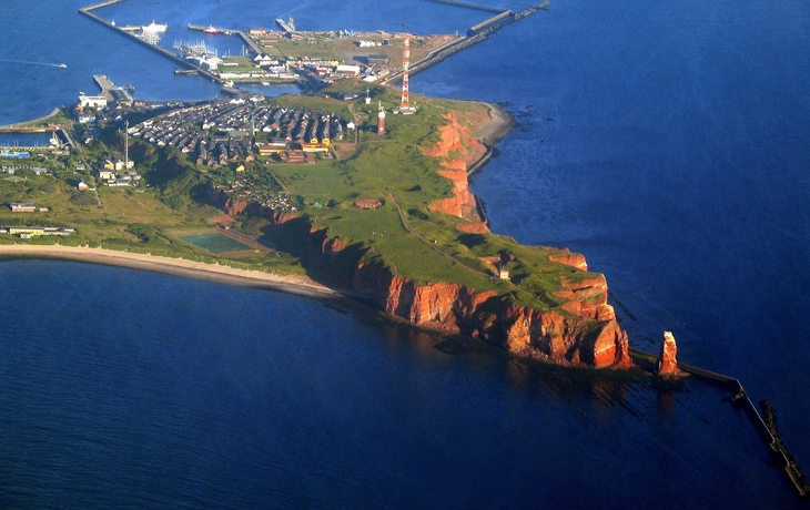 Luftaufnahme der Insel Helgoland mit roter Felsküste und Nordsee im Hintergrund.