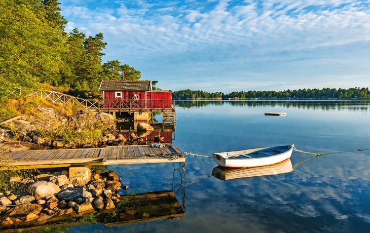 Schärengarten mit Bootshaus und Boot am Wasser, Stockholm, Schweden