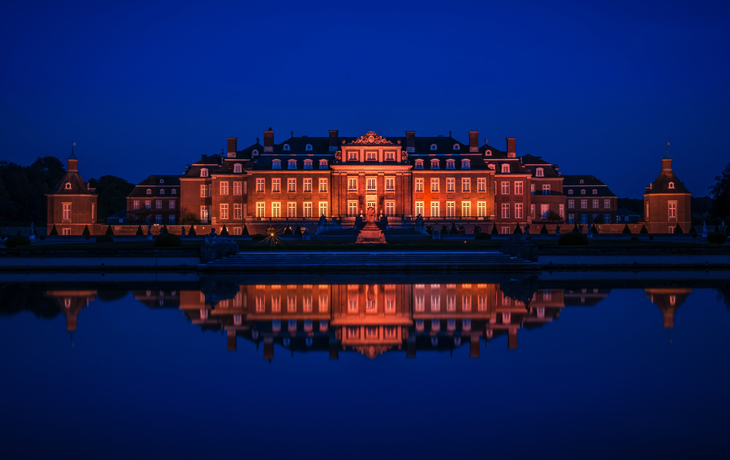 Schloss Nordkirchen bei Nacht, beleuchtet, mit Spiegelung im See.