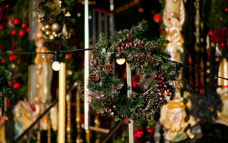 Weihnachtskranz mit roten Beeren und Lichtern auf einem festlichen Markt in Edinburgh.