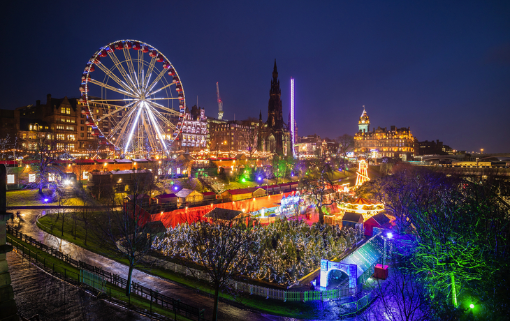 Edinburgh Altstadt bei Nacht mit beleuchtetem Riesenrad und Winterfest-Stimmung.