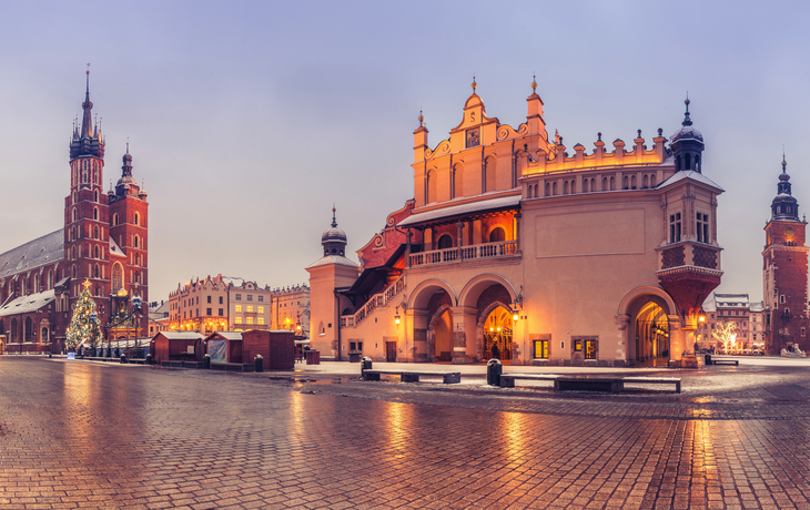 Dämmerung am Hauptmarkt in Krakau mit Marienkirche und Tuchhallen im Schnee.