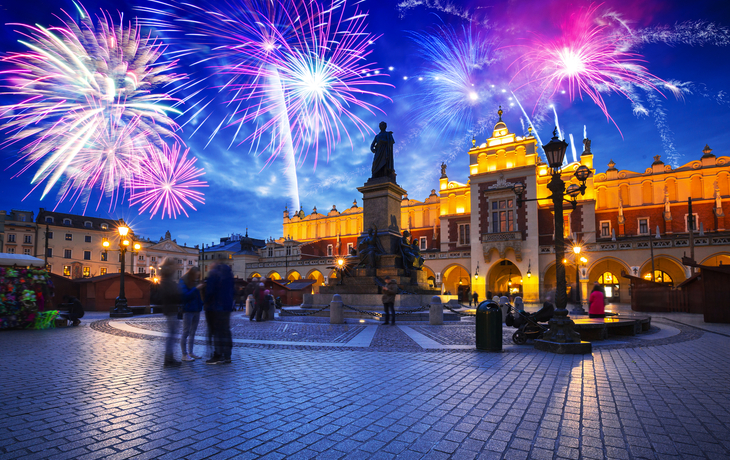Feuerwerk über dem beleuchteten Hauptmarkt in Krakau bei Nacht zu Silvester.