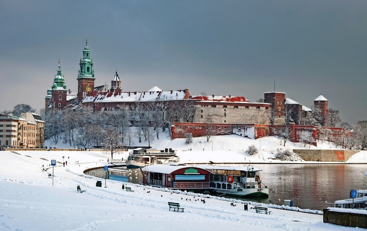 Winterliche Burg Wawel in Krakau mit Schnee und Weichsel im Vordergrund.