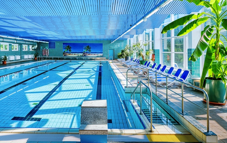 Innenpool mit Liegestühlen und Pflanzen im AHORN Berghotel Friedrichroda.