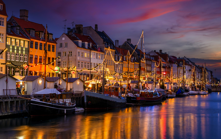 Nyhavn in Kopenhagen bei Nacht, beleuchtet im Winter zu Weihnachten am Hafen.