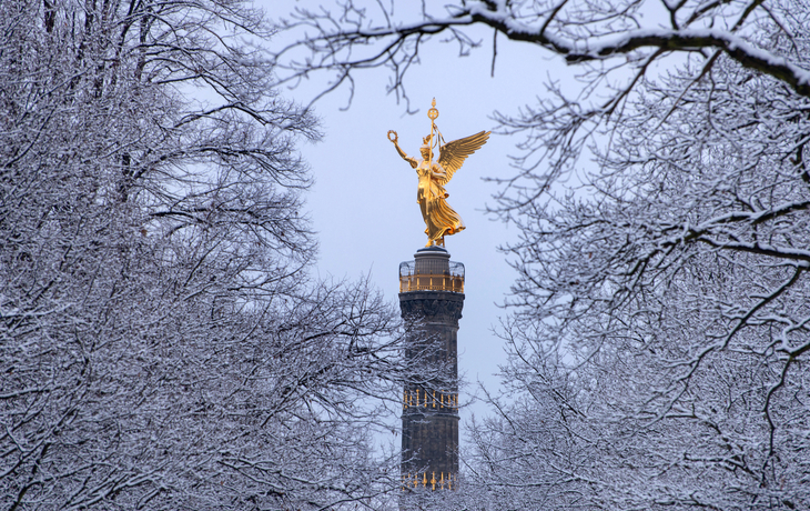 Siegessäule in Berlin, umgeben von schneebedeckten Bäumen im Winter.