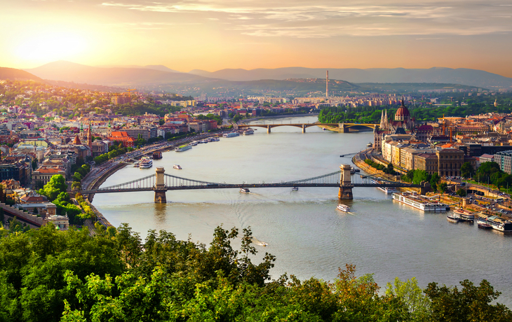 Panorama von Budapest mit Donau, Kettenbrücke und Parlamentsgebäude bei Sonnenuntergang.