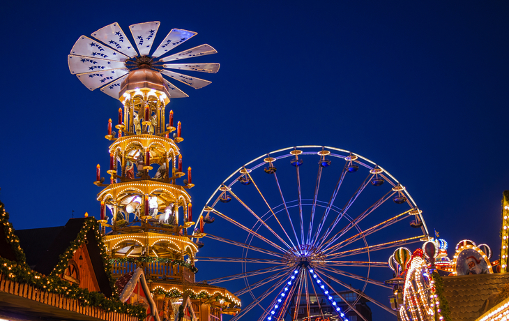 Weihnachtspyramide und Riesenrad auf dem Weihnachtsmarkt in Rostock bei Nacht.