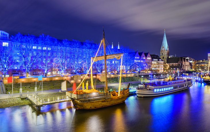 Nachtaufnahme von beleuchteten Schiffen am Weihnachtsmarkt in Bremen, Deutschland.