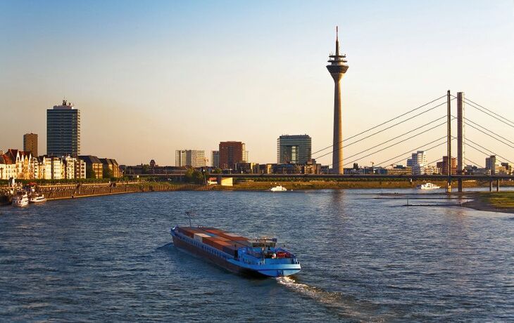 Panorama von Düsseldorf mit Rheinturm und Rheinpromenade im Medienhafen bei Sonnenuntergang.