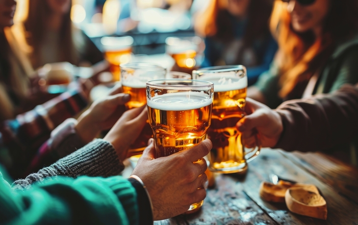 Freunde stoßen mit Biergläsern in rustikaler Bar an.