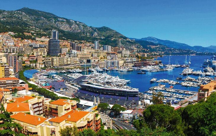 Blick auf Monte Carlo mit Yachthafen, Hochhäusern und Küstengebirge in Südfrankreich.