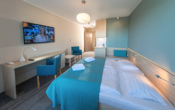 Doppelzimmer mit Bett, Schreibtisch, TV und blauen Akzenten