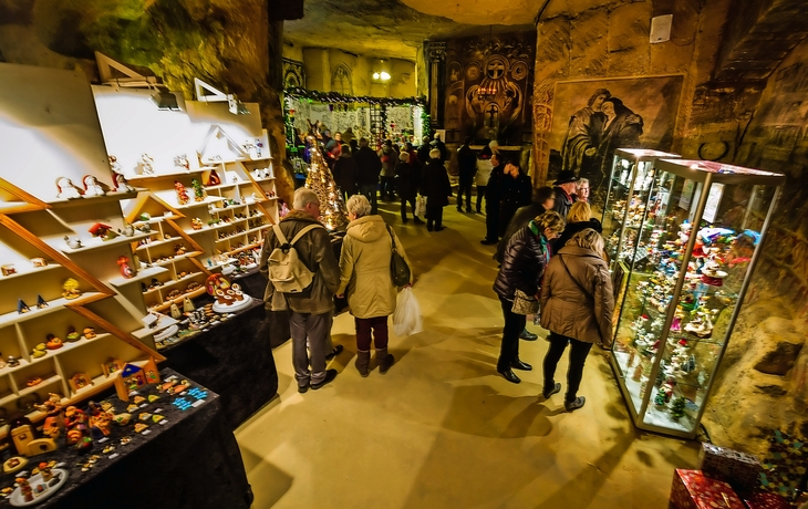 Unterirdischer Weihnachtsmarkt mit Kunsthandwerk und Besuchern in der Fluweelengrotte.