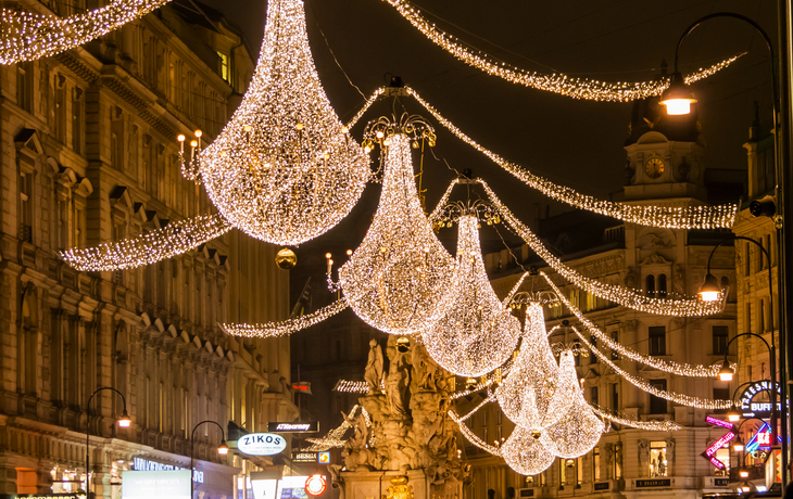 Lichterketten illuminieren Straße mit historischen Gebäuden bei Nacht.