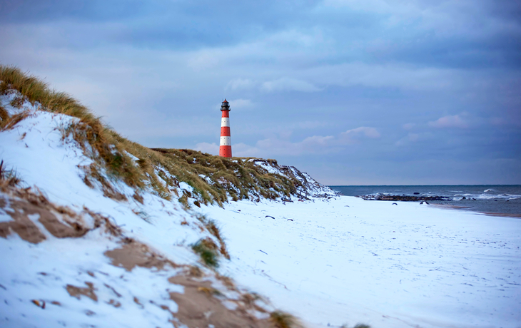 Verschneiter Sandstrand auf Sylt mit Dünen und Nordsee im Winter.