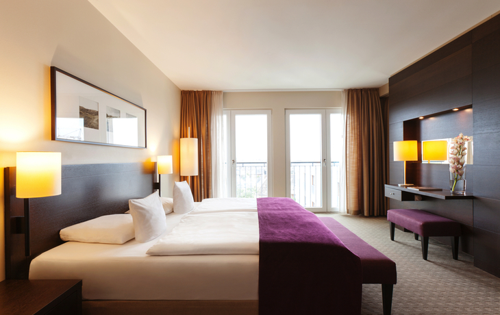 Modernes Hotelzimmer mit zwei Betten, Schreibtisch und großen Fenstern
