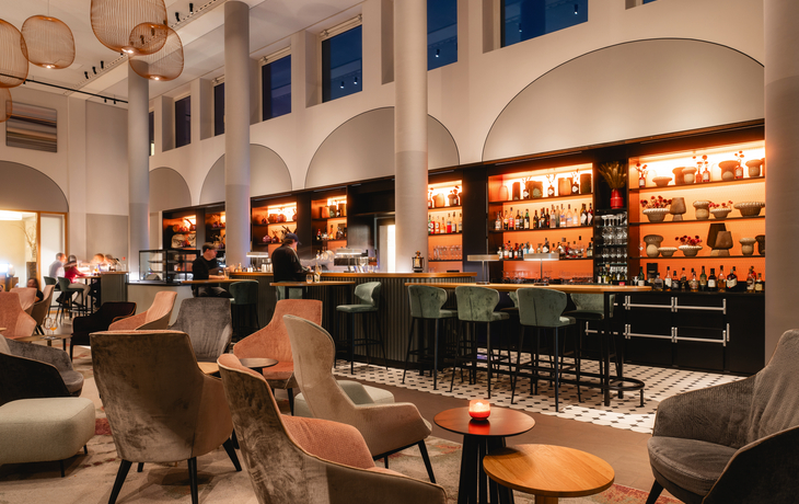 Bar im A-ROSA Hotel Sylt mit gemütlichen Sitzgelegenheiten und beleuchteter Theke.