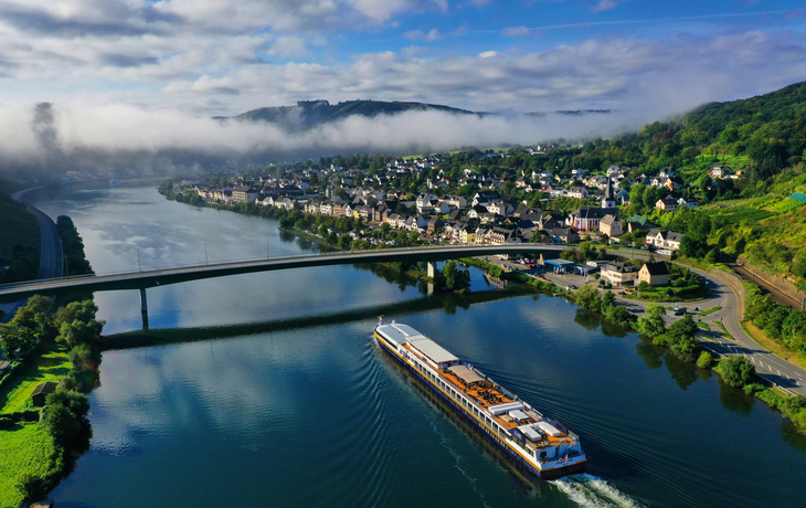 Flussschiff MS Elegant Lady auf der Mosel vor einer Stadt im Hintergrund.