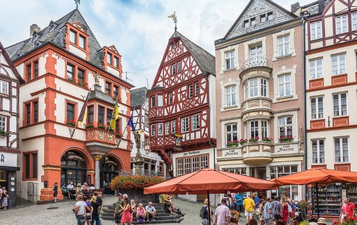 Historischer Marktplatz in Bernkastel mit Fachwerkhäusern und Rathaus, Menschen flanieren.