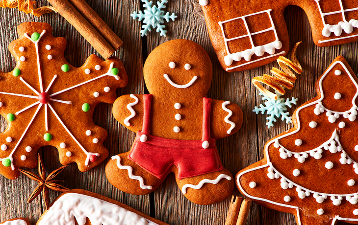 Lebkuchen in Form eines Männchens und anderer Figuren auf einem Holztisch.