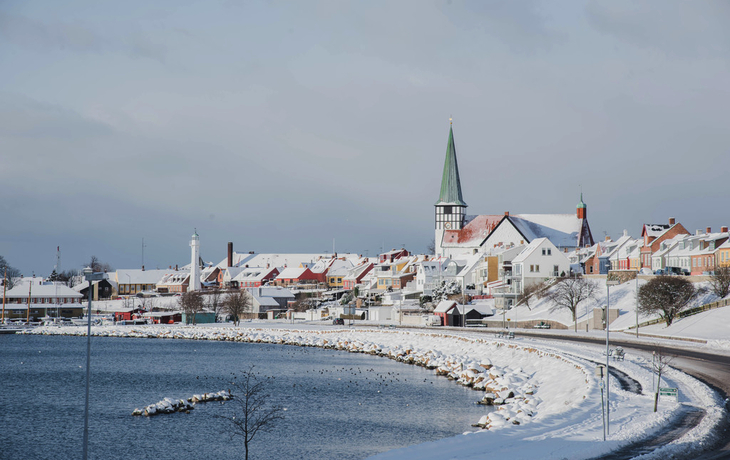 Verschneite Küstenstadt mit Kirche und bunten Häusern in Rønne, Bornholm.