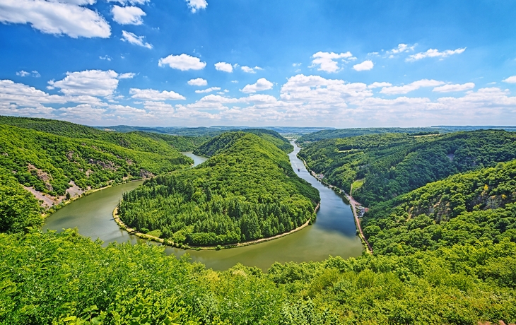 Saarschleife im Saarland mit umliegenden Wäldern und blauem Himmel.