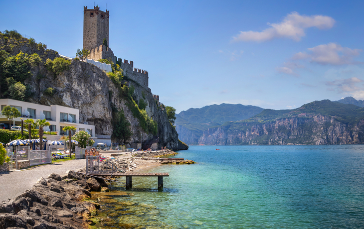 Uferbereich von Malcesine am Gardasee mit Burg und Bergen.