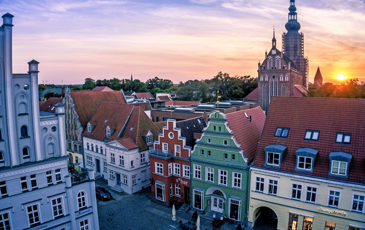 Ein alter, bunter Marktplatz mit historischen Gebäuden im Sonnenuntergang.