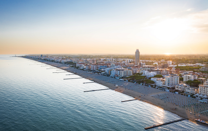 Küstenpanorama mit Strandpromenade und Hochhäusern bei Sonnenuntergang.
