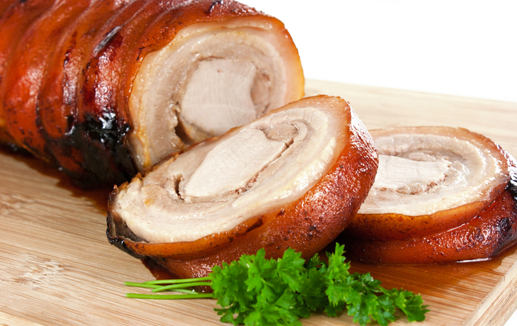 Nahaufnahme eines knusprigen Schweinebratens mit Petersilie.